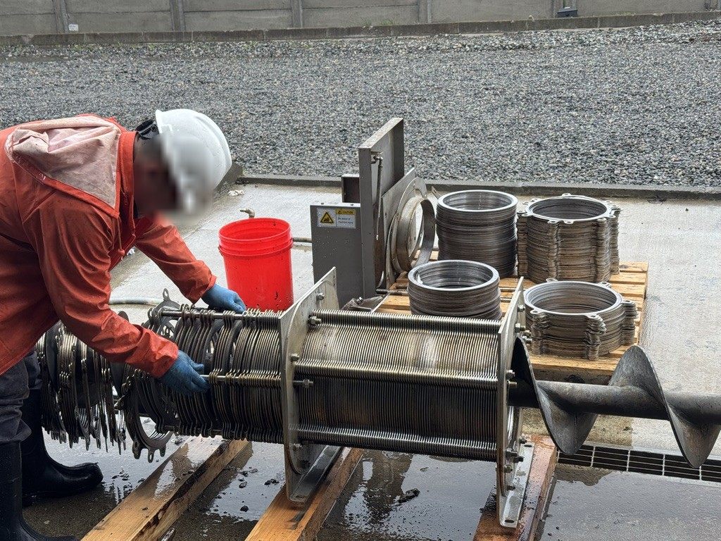 Técnico con casco realizando mantención de equipo de filtrado de lodos